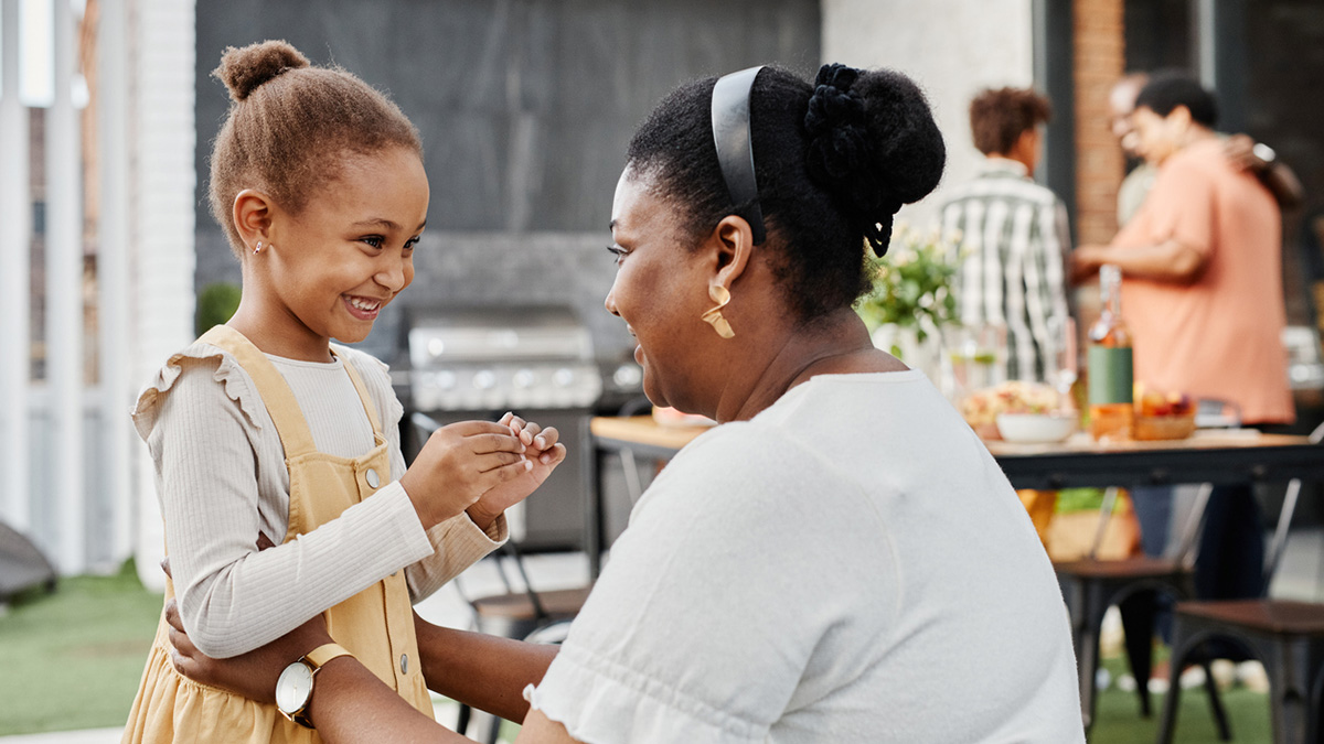 Portrait of African-American woman talking to cute little girl at party outdoors (1343793416)