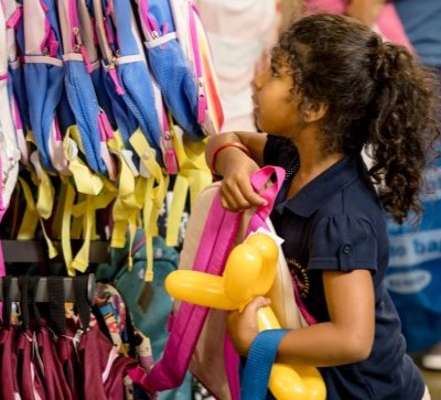 Voices for Children partnered with Old Navy Back for the annual Back to School Event.  A female child has a new backpack and a balloon animal. 